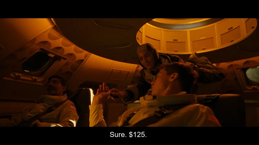 Movie still from Ad Astra (2019) showing the interior of a spacecraft with orange/yellow lighting. A flight attendant stands over Brad Pitt's character who is seated and strapped in, with other passengers visible in the background. Subtitles read: 'Sure. $125.'
